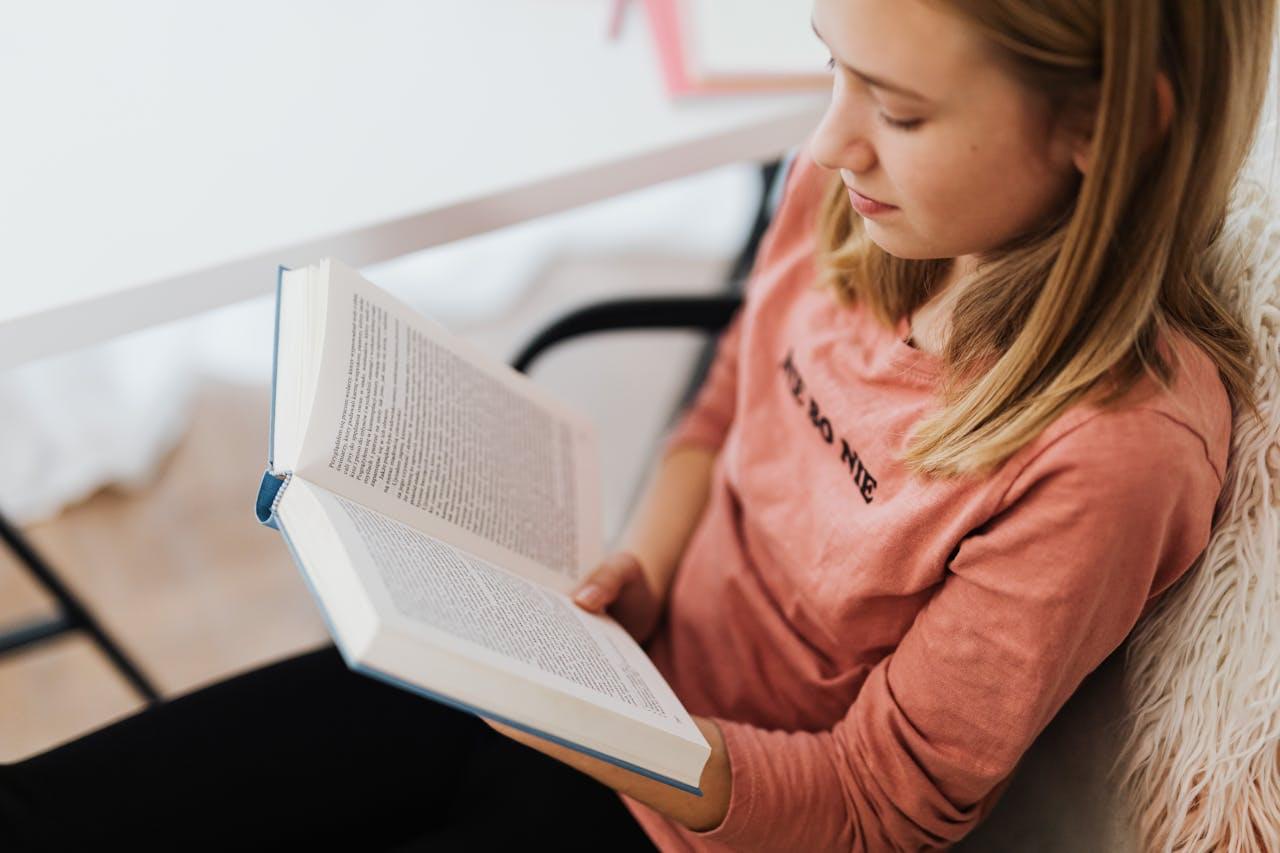 Девушка читает книгу в кресле